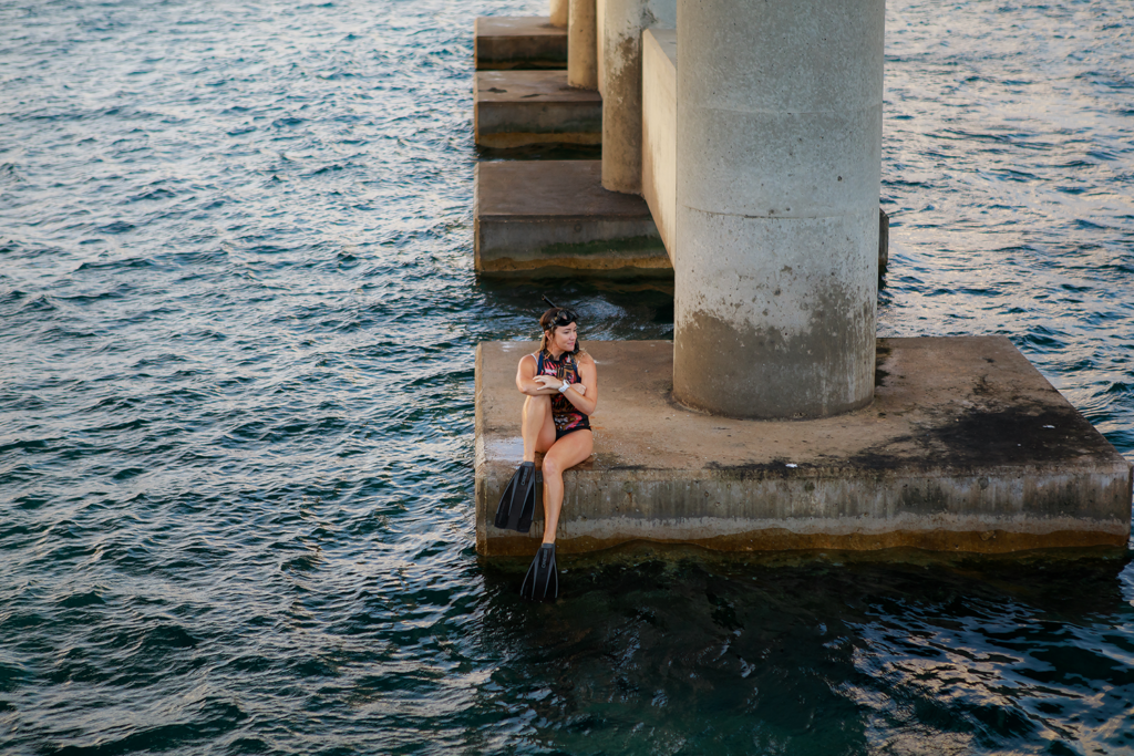 ashley taylor, the founder of citizen yard and a b corp consultant sits on a seawall after snorkeling